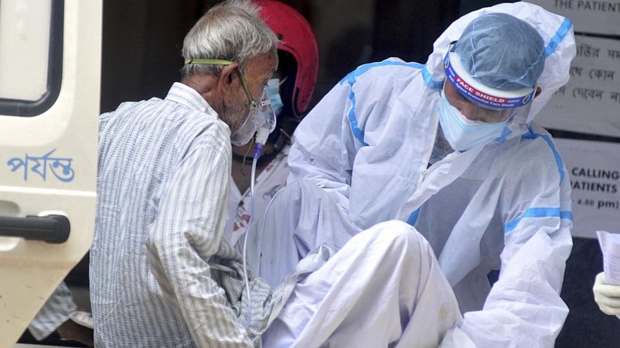 A health worker helps a Covid-19 patient during his admission at a state government run hospital in Kolkata/ Credit: PTI Photo