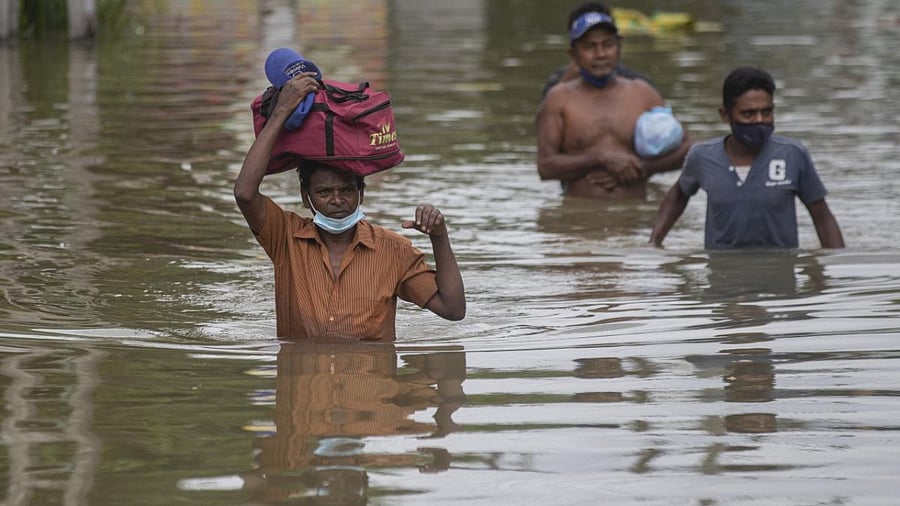 Sri Lankans wade through an inundated street following heavy rainfall at Malwana, on the outskirts of Colombo, Sri Lanka. Credit: AP Photo