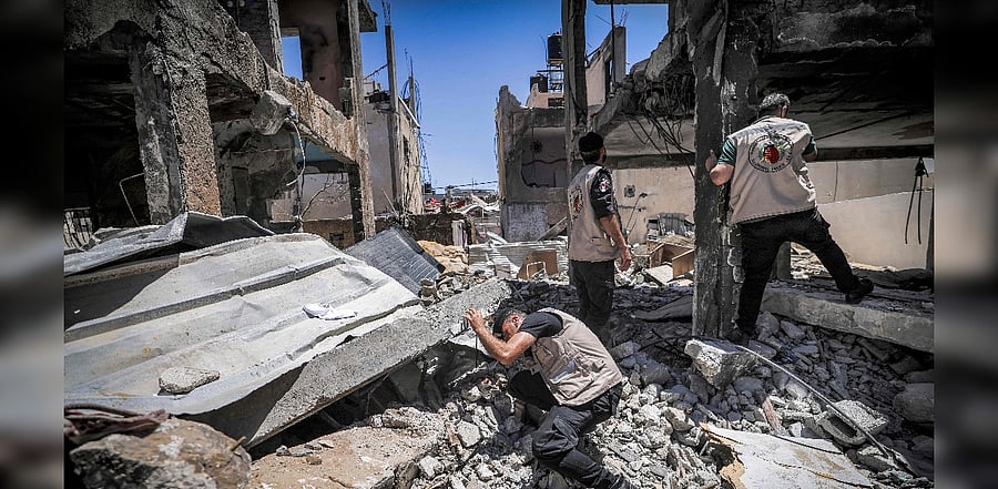Explosives experts of Hamas search a destroyed building for unexploded projectiles. Credit: AFP Photo