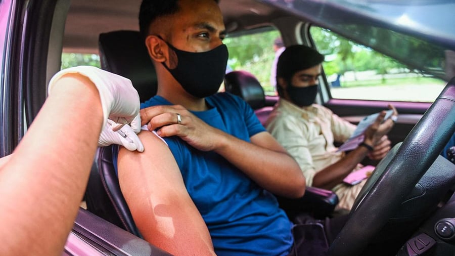 A health worker inoculates a youth with a dose of the Covishield vaccine at a drive-in vaccination facility in New Delhi. Credit: AFP Photo