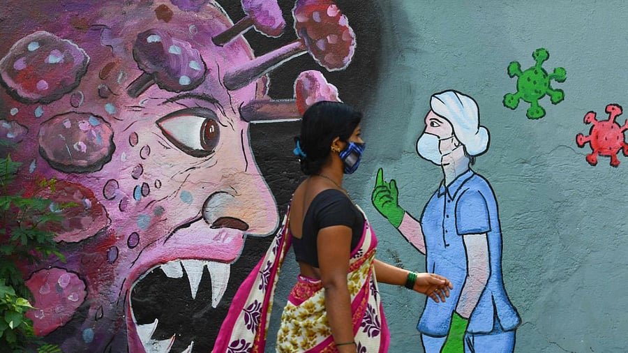 A pedestrian walks past a wall mural depicting a frontline medical staff stopping the Covid-19, in Navi Mumbai. Credit: AFP Photo