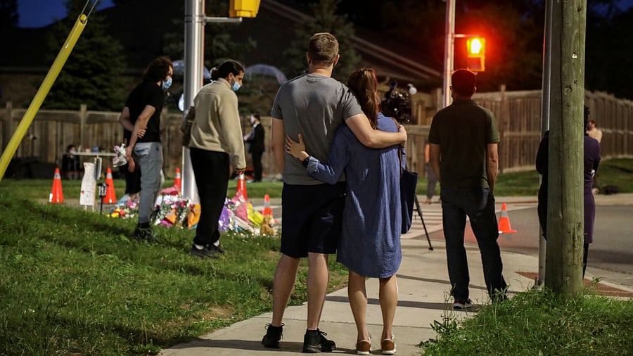 People and members of the media are seen at a makeshift memorial at the fatal crime scene where a man driving a pickup truck jumped the curb and ran over a Muslim family in what police say was a deliberately targeted anti-Islamic hate crime, in London, Ontario. Credit: Reuters photo