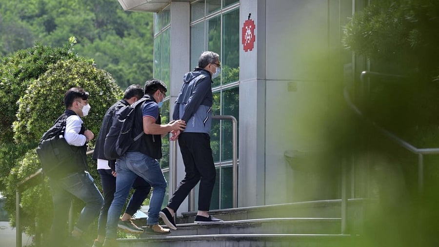 Cheung Kim Hung (C), CEO and Executive Director of Next Digital Ltd, is escorted by police into the Apple Daily newspaper offices in Hong Kong. Credit: AFP Photo