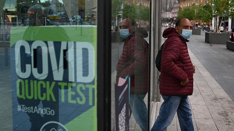 A man wearing a face-covering passes a Covid-19 information sign as he exits the Bus Station in Blackburn, northwest England. Credit: AFP Photo