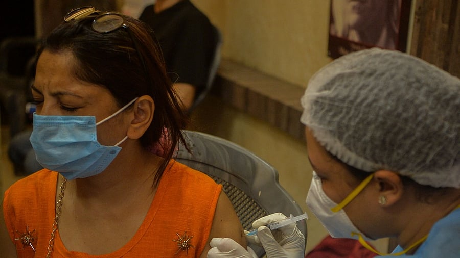 A health worker inoculates a woman with the jab of Covid-19 coronavirus vaccine at a camp set up in a market association's office in Siliguri on June 22, 2021. Credit: AFP Photo