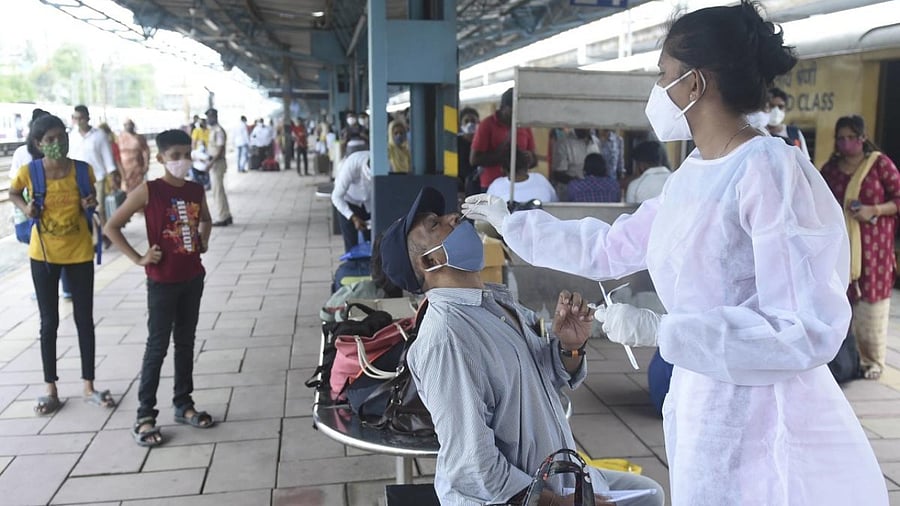 A BMC health worker collects swab sample of a passenger for Covid-19 testing, at Dadar railway station in Mumbai. Credit: PTI Photo