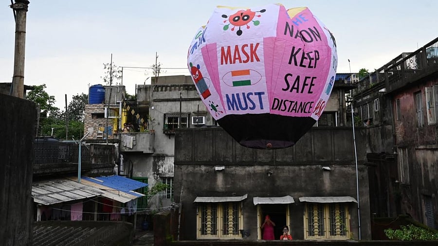Residents take pictures of a paper lantern released with Covid-19 guidelines to create awareness in Kolkata. Credit: AFP Photo