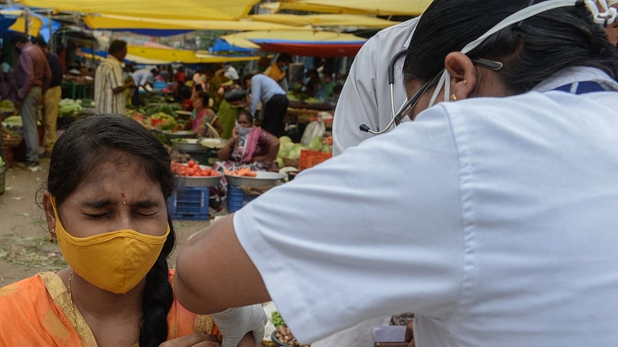 A health worker inoculates a woman with a dose of the Covishield vaccine against the Covid-19 coronavirus during a vaccination drive at a vegetable market in Hyderabad on June 24, 2021. Credit: AFP Photo