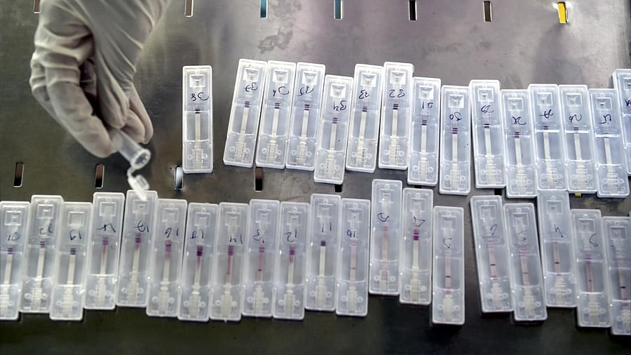 A BMC health worker observes a swab sample of a passenger for Covid-19 test, at Dadar railway station in Mumbai. Credit: PTI Photo