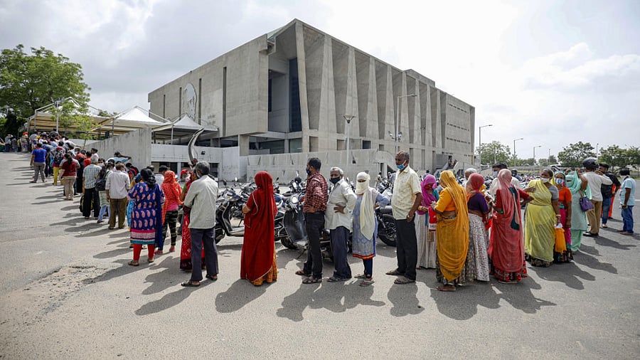 Beneficiaries wait in a queue to receive the Covid-19 vaccine dose, at a community hall in Ahmedabad. Credit: PTI Photo