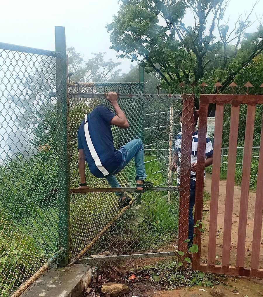 Tourists gain entry to Mallalli Falls through the broken enclosure.