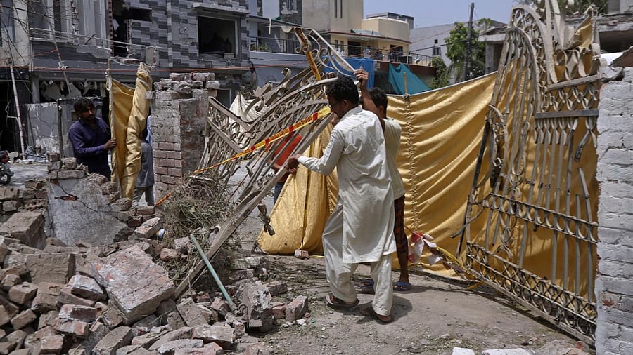  Residents remove a gate from their damaged house at the site of the car bombing. Credit: AP Photo