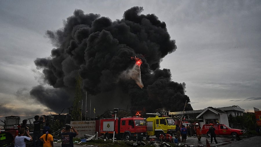 A helicopter dumps water onto the site of an explosion and fire at a plastics factory on the outskirts of Bangkok. Credit: AFP Photo
