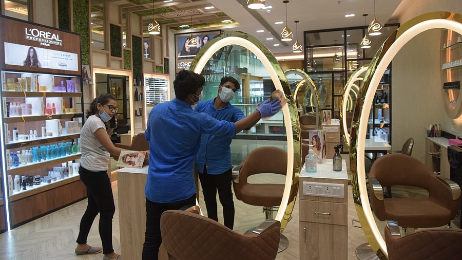 A worker cleans a mirror in a store at Orion Mall in Bengaluru ahead of its reopening. Credit: DH Photo/B H Shivakumar
