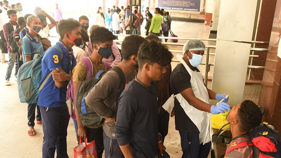 A health worker collects samples from passenger for Covid-19 at KSR Railway Station in Bengaluru on Sunday. Credit: DH Photo/ B H Shivakumar