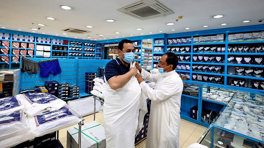 Egyptian Mohammed Alatar (L), 31, tries on Ihram, a simple garment representing a state of holiness worn by pilgrims performing the Hajj, at a local store in Saudi Arabia's capital Riyadh, on July 10, 2021, after he won a place to perform the yearly pilgrimage for the 2021 season. Credit: AFP Photo