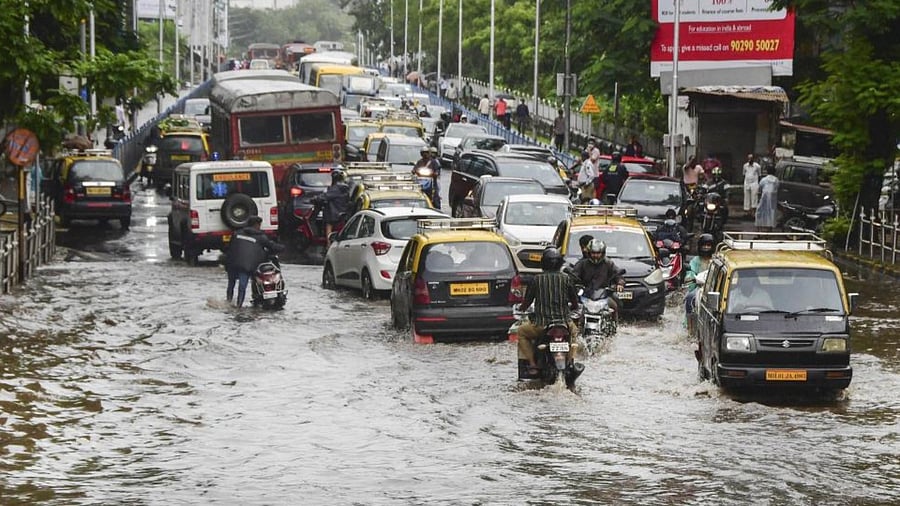 Commuters wade through a waterlogged road at Dadar after heavy rains in Mumbai. Credit: PTI Photo