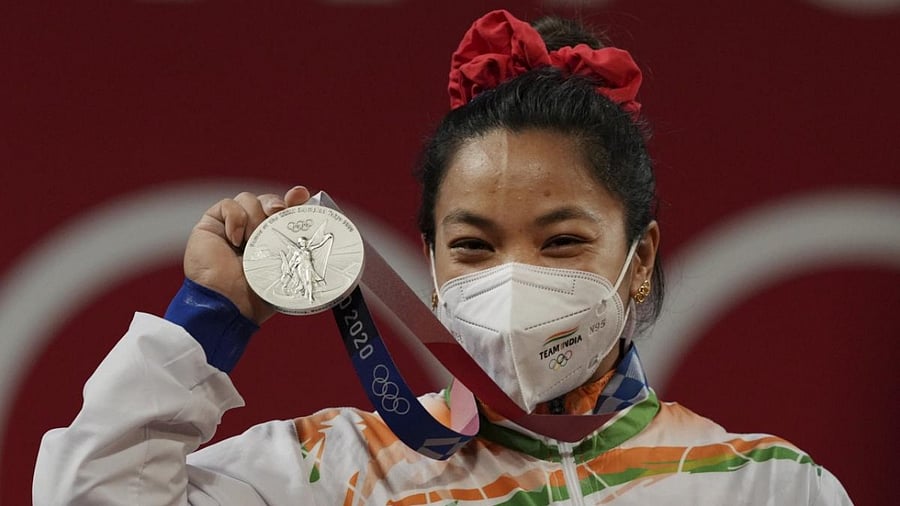 India's Mirabai Chanu wearing golden Olympic Rings ear-ring poses for photographs while standing on the podium after receiving the silver medal in women's 49 kg category weightlifting event at the Summer Olympics 2020, in Tokyo, Saturday, July 24, 2021. Credit: PTI Photo