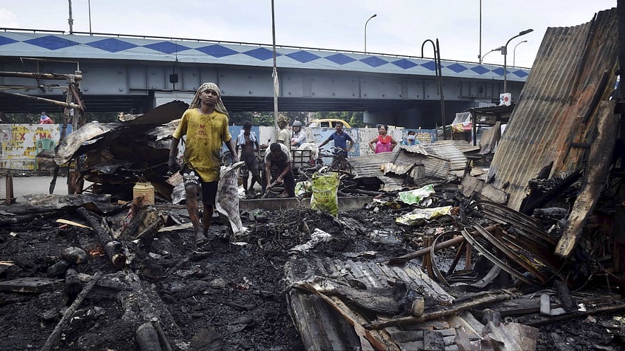 People stand near the debris of a shop and house destroyed after a fire broke out at Kolkata's Kestopur area. Credit: PTI Photo