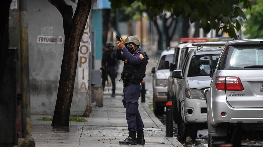 A member of the Bolivarian Police aims at a possible target after clashes with alleged members of a criminal gang at the Cota 905 neighborhood, in Caracas. Credit: AFP Photo