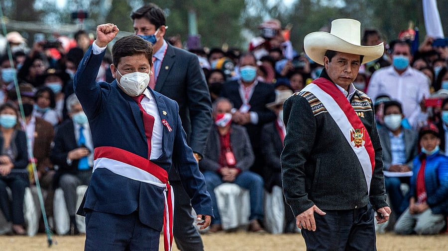 Peru's new Chief of Staff Guido Bellido (L) raises his fist next to Peru's President Pedro Castillo (R) at Pampa de la Quinua in Ayacucho, southern Peru. Credit: AFP Photo