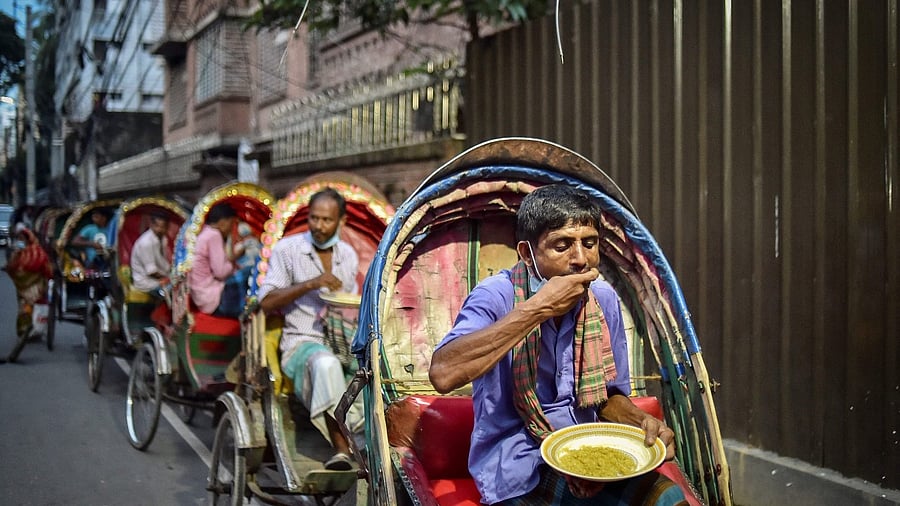 Pandemic affected people eating food distributed by Mehmankhana, a non-profit organization, in Bangladesh. Credit: AFP Photo