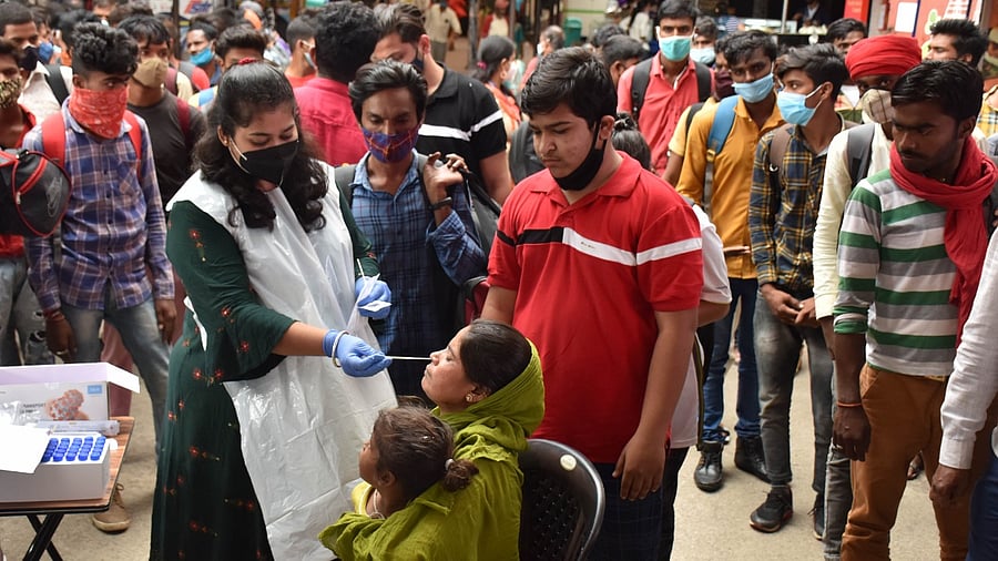 A health worker collecting swab samples from passengers at the KSR railway station in Bengaluru on Wednesday. Credit: DH Photo