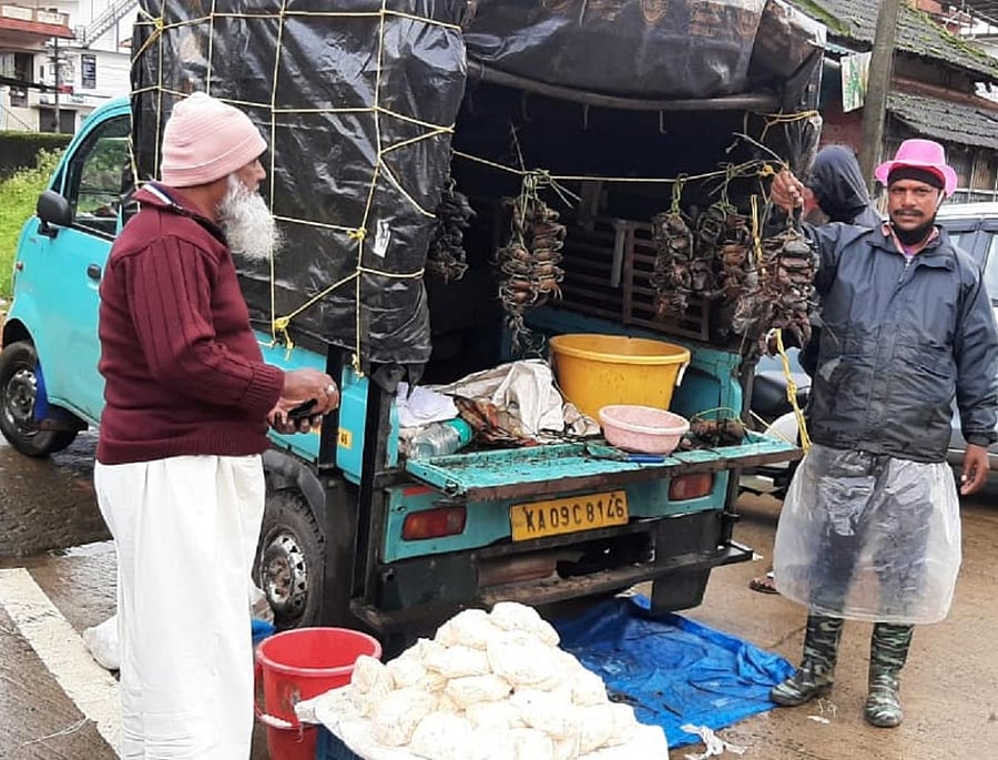 A man sells crabs and bamboo shoots beside a road in Virajpet.