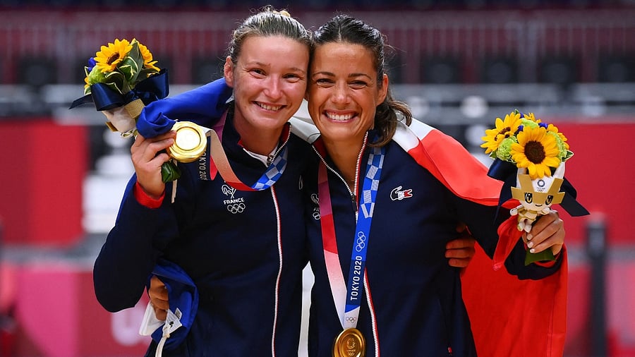 France's goalkeeper Amandine Leynaud (L) and France's goalkeeper Cleopatre Darleux celebrate with their gold medals on the podium after the women's handball event of the Tokyo 2020 Olympic Games at the Yoyogi National Stadium in Tokyo. Credit: AFP photo