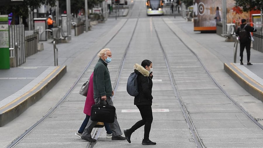 People cross a quiet street in Melbourne's central business district on August 11, 2021 as five million people in Australia's second-largest city will remain under stay-at-home orders for at least another week. Credit: AFP Photo