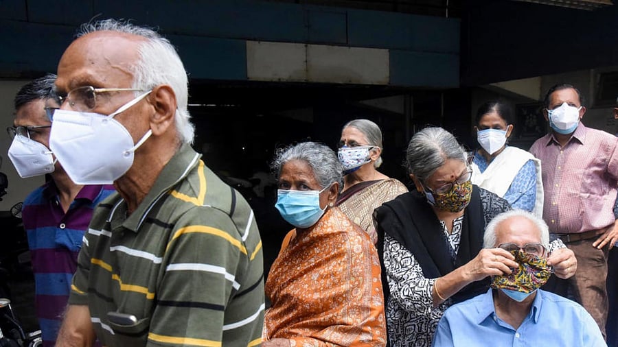 A woman puts a mask to her husband while waiting for vaccination against Covid-19, in Kochi, Saturday, May 8, 2021. Credit: PTI Photo