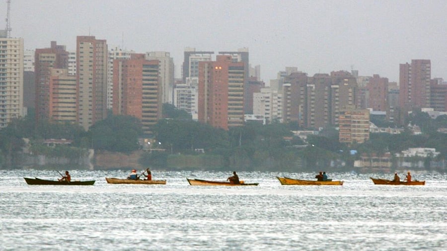 Fishermen steer their boats in the Maracaibo Lake, Zulia State, Venezuela, on July 30, 2021. - Franklin relies on the wind to power his small sailboat. Manuel, a former bus driver, carries passengers in a "bicitaxi". Both manage to survive the chronic fuel shortages in Zulia, the region that saw the birth of Venezuela's oil industry. Credit: AFP Photo