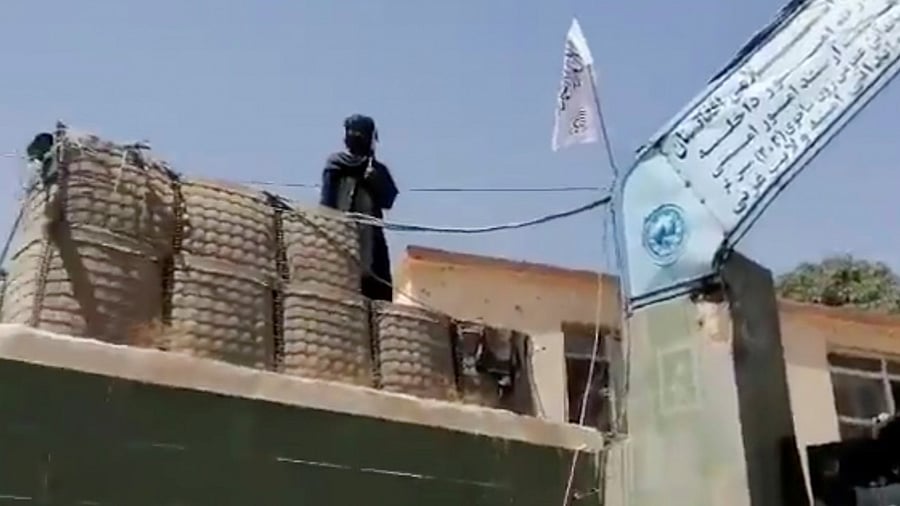 A fighter stands guard next to a Taliban flag. Credit: Reuters Photo