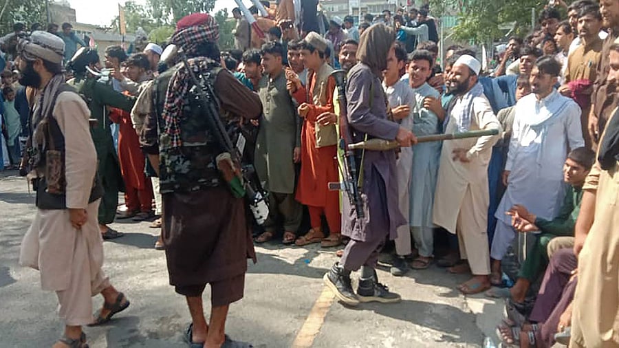 Taliban fighters and local people are pictured along the street in Jalalabad province. Credit: AFP Photo