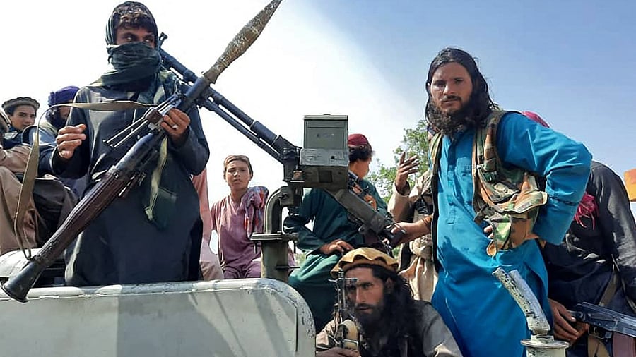 Taliban fighters sit over a vehicle on a street in Laghman province. Credit: AFP Photo