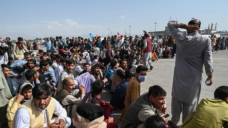 Afghan passengers sit as they wait to leave the Kabul airport. Credit: AFP Photo