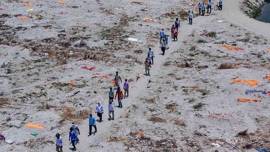 Family members and relatives return after burying a dead body, near the banks of river Ganga at Phaphamau Ghat in Prayagraj. Credit: PTI Photo