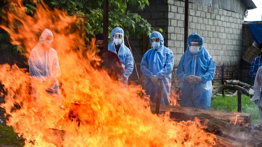 Relatives of a Covid-19 victim perform last rites during the cremation ceremony, at a crematorium in Srinagar. Credit: PTI Photo
