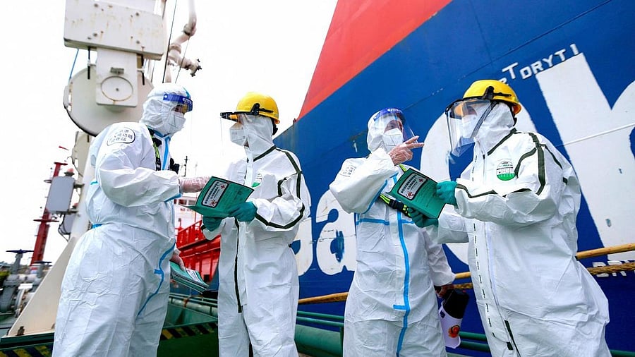 Police officers explain pandemic prevention information to fight against the spread of Covid-19 coronavirus to workers at Nanjing port in China's eastern Jiangsu province on August 4, 2021. Economists are already paring their growth forecasts for Asia as real-time indicators show a hit to consumption and other activity. Credit: AFP file photo
