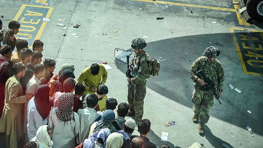 US soldiers stand guard as Afghan people wait at the Kabul airport. Credit: AFP Photo