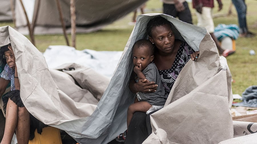 People gather after spending the night outside in the aftermath of the earthquake, facing the severe inclement weather of Tropical Storm Grace near Les Cayes, Haiti. Credit: AFP Photo