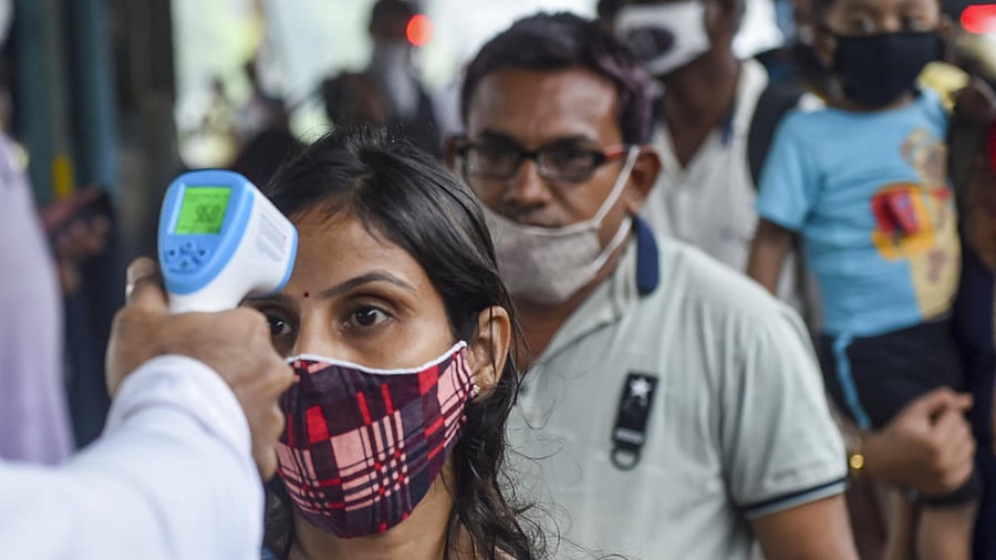 A BMC health worker does thermal screening of a passenger for Covid-19 test, at Dadar railway station in Mumbai. Credit: PTI Photo