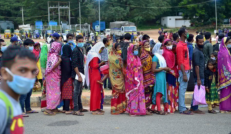 Migrants stand in queues at Palace Ground for their onward journey to their native places via 'Sharmik Special' train, during the ongoing COVID-19 nationwide lockdown, in Bengaluru. Credits: PTI Photo