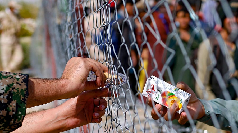 An Iranian soldier distributing boxes of juice to Afghan refugees gathered at the Iran-Afghanistan border between Afghanistan and the southeastern Iranian Sistan and Baluchestan province. Credit: AFP Photo