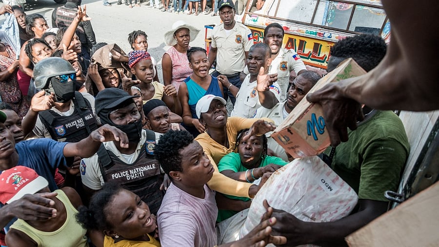 Police officers monitor the crowd as earthquake victims receive supplies during the distribution of food and water in Les Cayes. Credit: AFP Photo