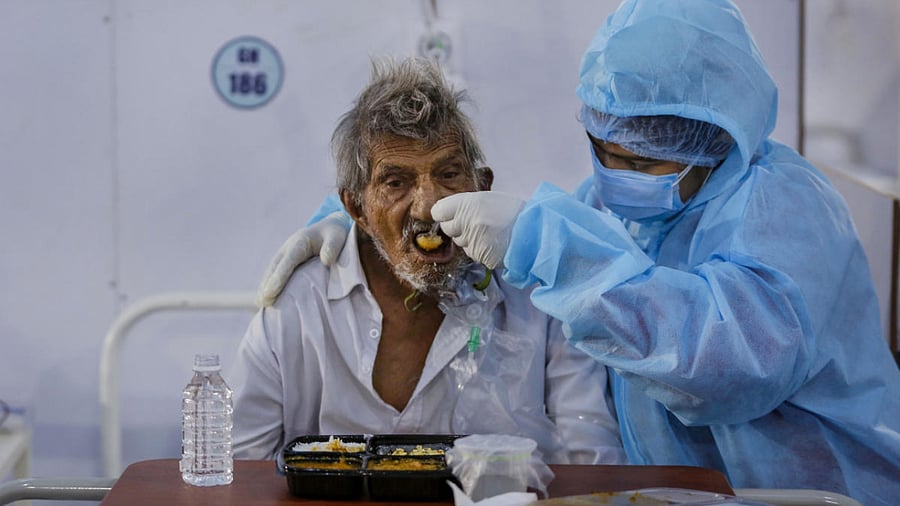 A health worker feeds a Covid-19 patient inside Dhanvantri Covid hospital, in Ahmedabad. Credit: PTI Photo