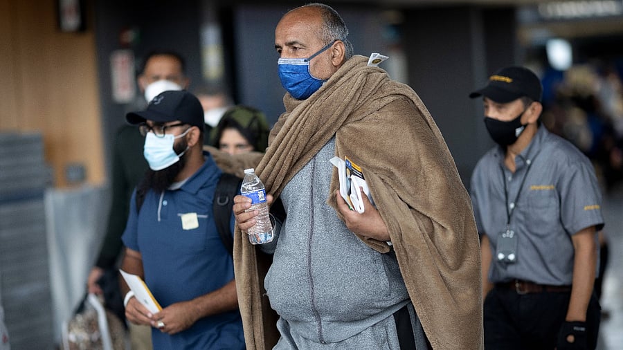 Refugees evacuated from Kabul Afghanistan walk from Dulles International Airport to a bus that will take them to a refugee processing center on August 26, 2021 in Dulles, Virginia. Credit: AFP Photo