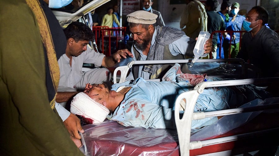 Medical and hospital staff bring an injured man on a stretcher for treatment after two blasts outside the airport in Kabul. Credit: AFP Photo