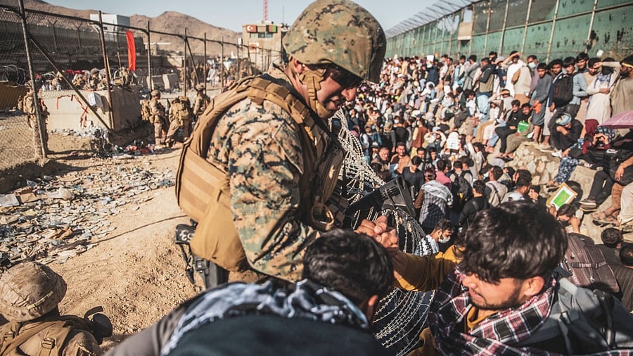 A US Marine assists at an Evacuation Control Check Point (ECC) during an evacuation at Hamid Karzai International Airport. Credit: Reuters File Photo