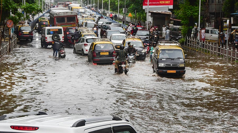 Commuters wade through a waterlogged road at Dadar after heavy rains in Mumbai, Sunday, July 18, 2021. Credit: PTI File Photo